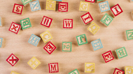 A collection of colorful wooden alphabet blocks scattered on a light surface.