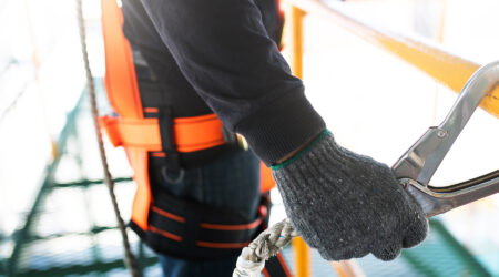Worker wearing safety harness and gloves for accident prevention.