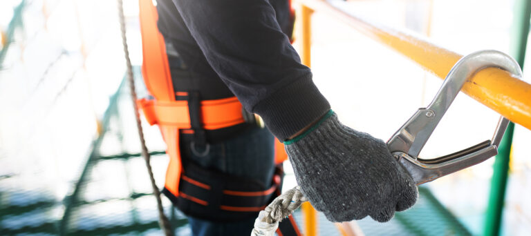 Worker wearing safety harness and gloves for accident prevention.