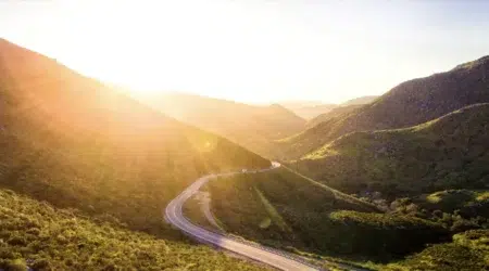 Sun rising over rolling green hills giving them a golden glow.