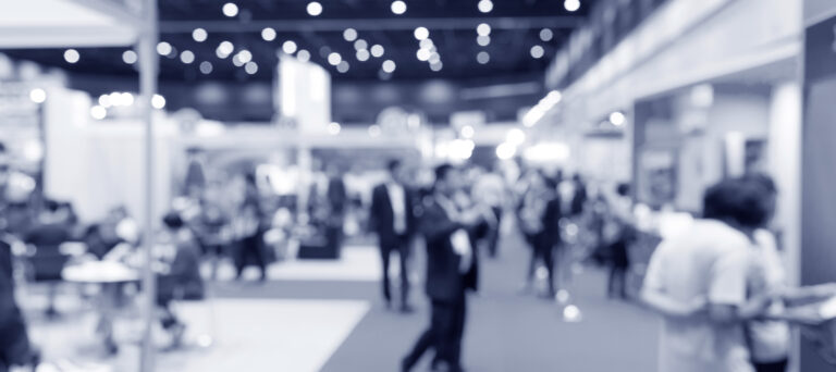 Crowd of people walking through an exhibition hall during a conference.