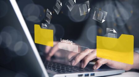 Digital content moving from one folder to another overlayed on person typing on laptop.