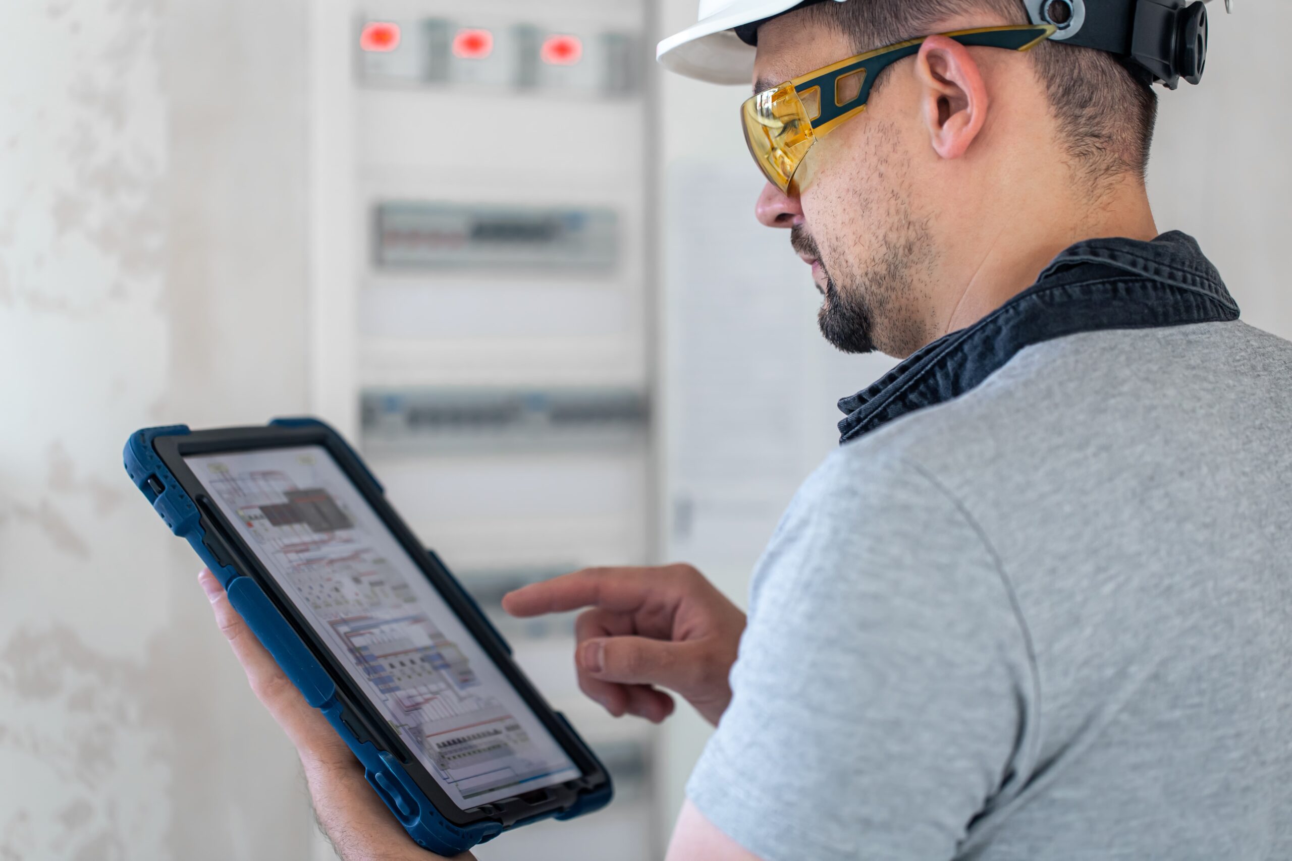 On site technician wearing protective gear and using tablet to look at technical diagrams.