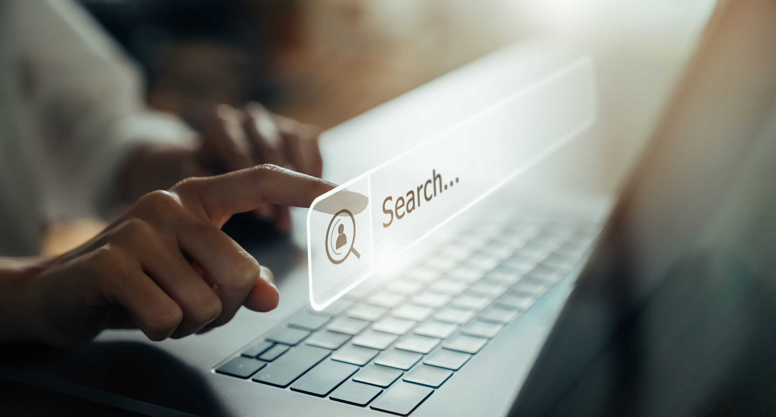 Close-up of a hand pressing a digital search bar on a laptop screen representing online browsing.
