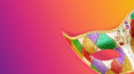 Colourful mask on a vibrant orange and purple gradient background.
