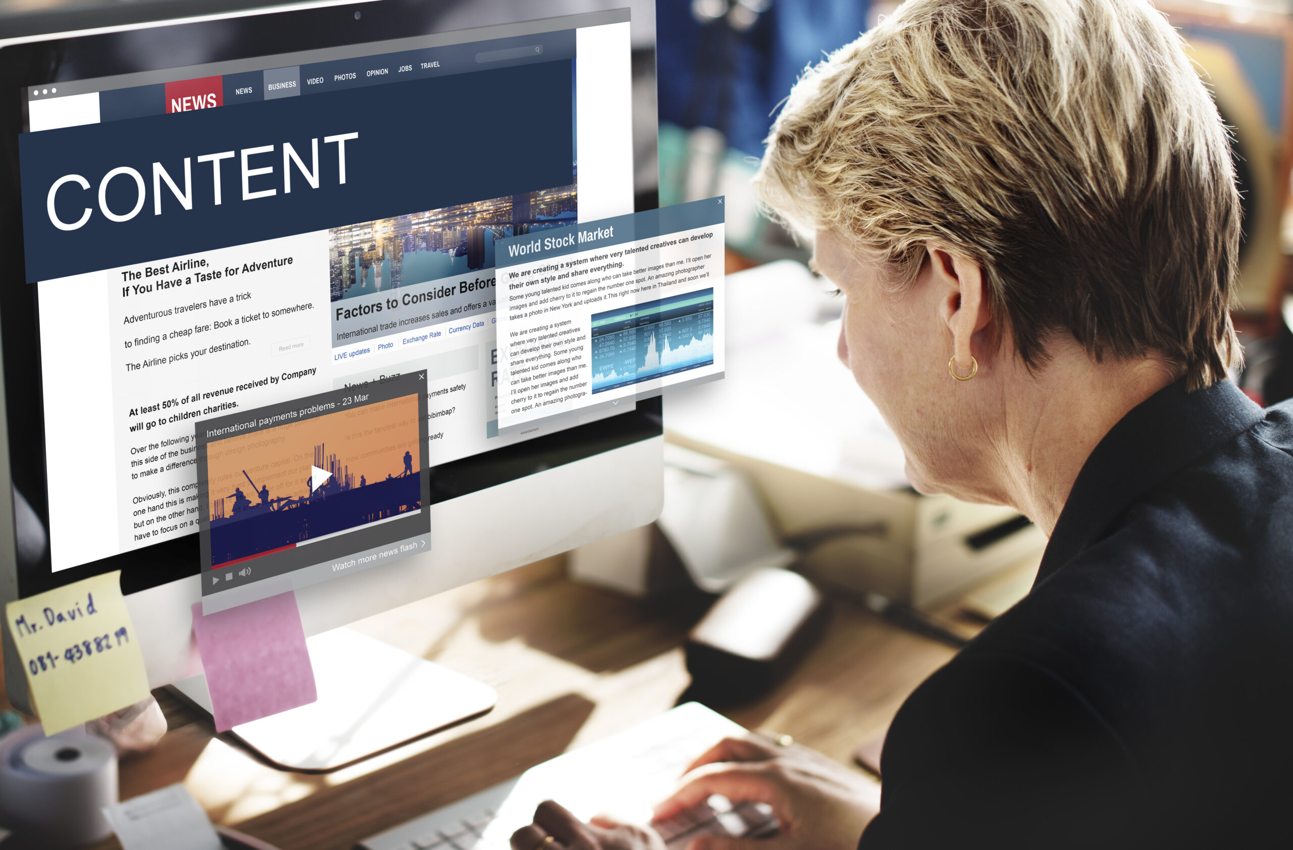 A person working on a computer displaying a website with the word "CONTENT" and various articles, alongside a video thumbnail.