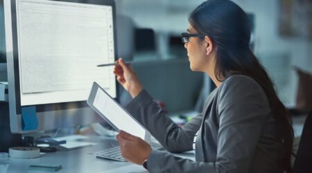 woman reviewing content on screen while holding tablet.
