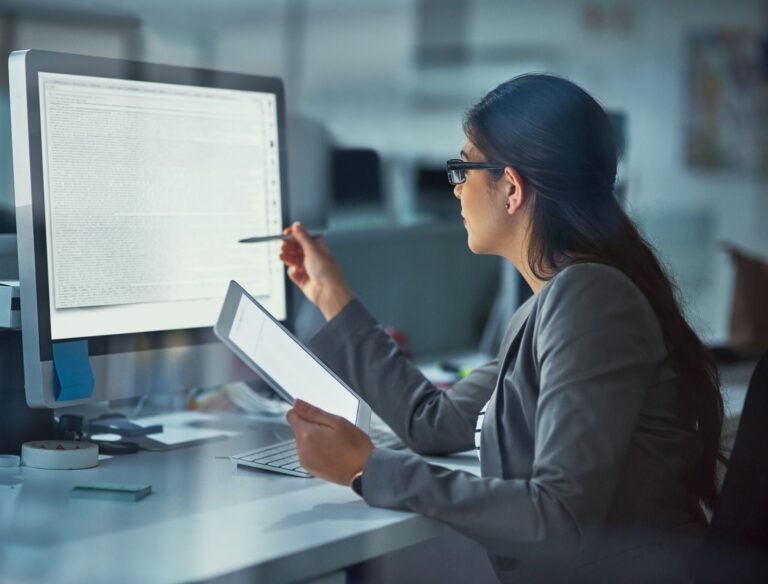 woman reviewing content on screen while holding tablet.