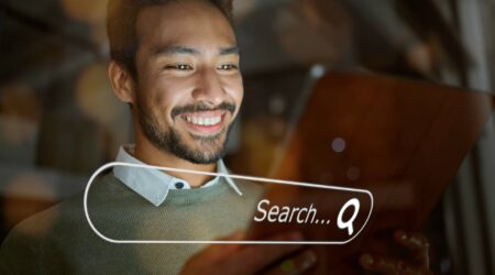 man smiling with tablet in hands and digital search bar overlayed.