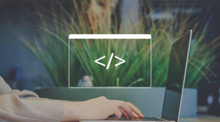 A person typing on a laptop with a code symbol overlay and greenery in the background.