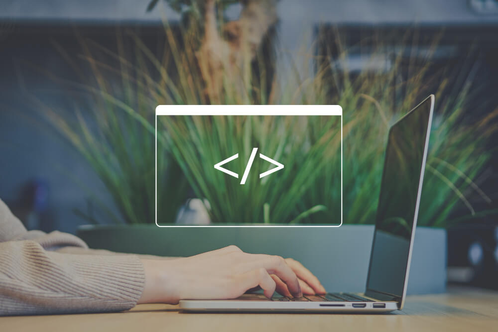 A person typing on a laptop with a code symbol overlay and greenery in the background.