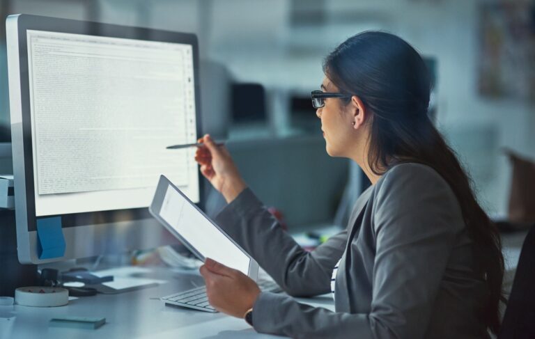 woman reviewing content on screen while holding tablet.