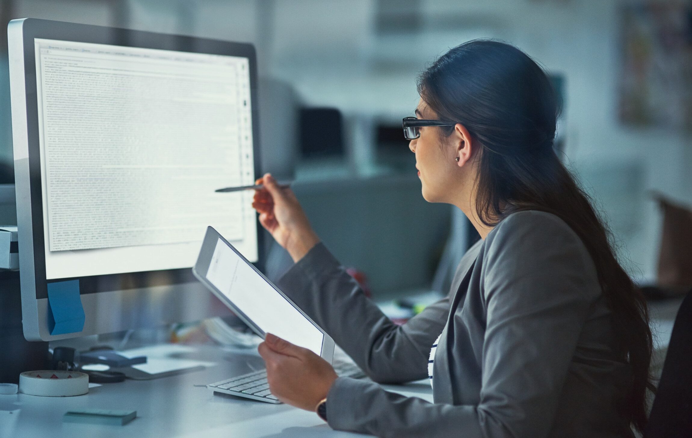 woman reviewing content on screen while holding tablet.