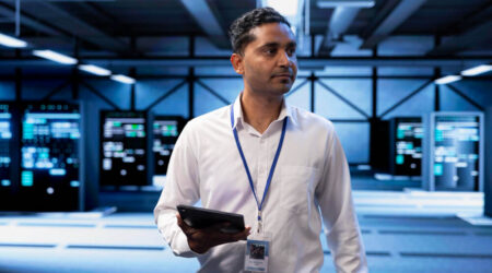 Man holding tablet walking through data servers.