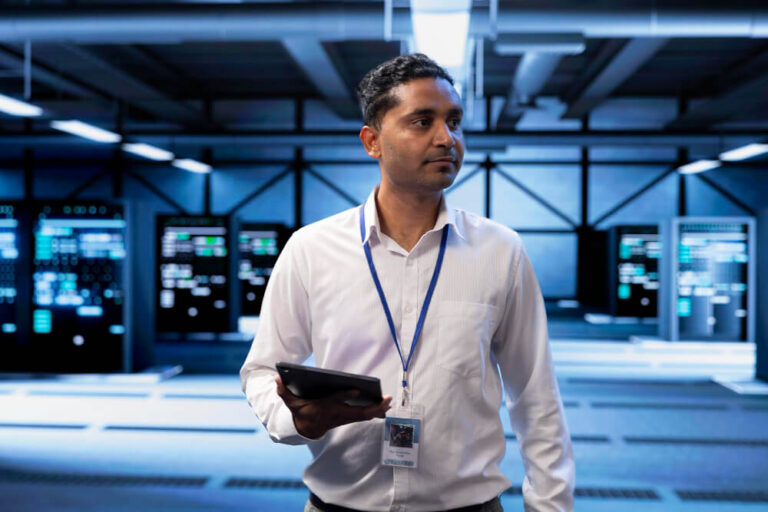 Man holding tablet walking through data servers.