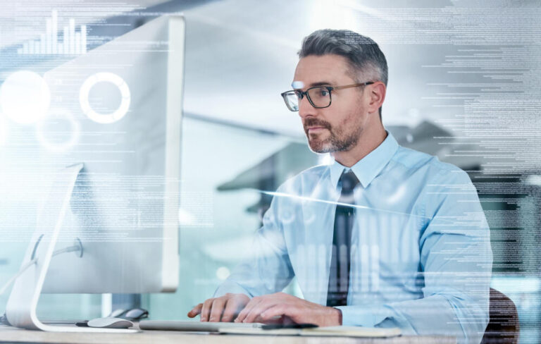 Man in a tie and button down shirt on a desktop computer with code and graphs digitally overlaid.