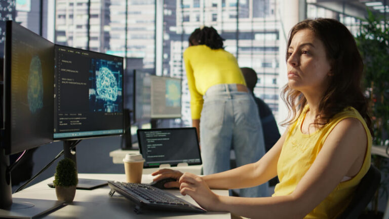 Woman sitting at office desk using AI software.
