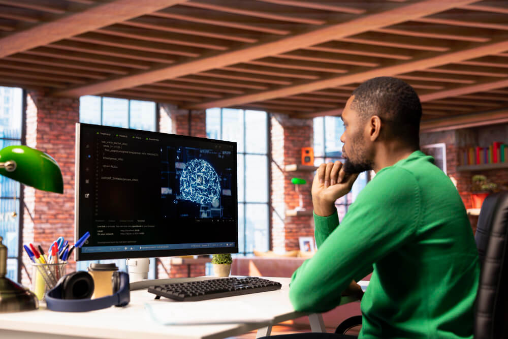 Man sitting at a desk looking at a computer screen that says AI.