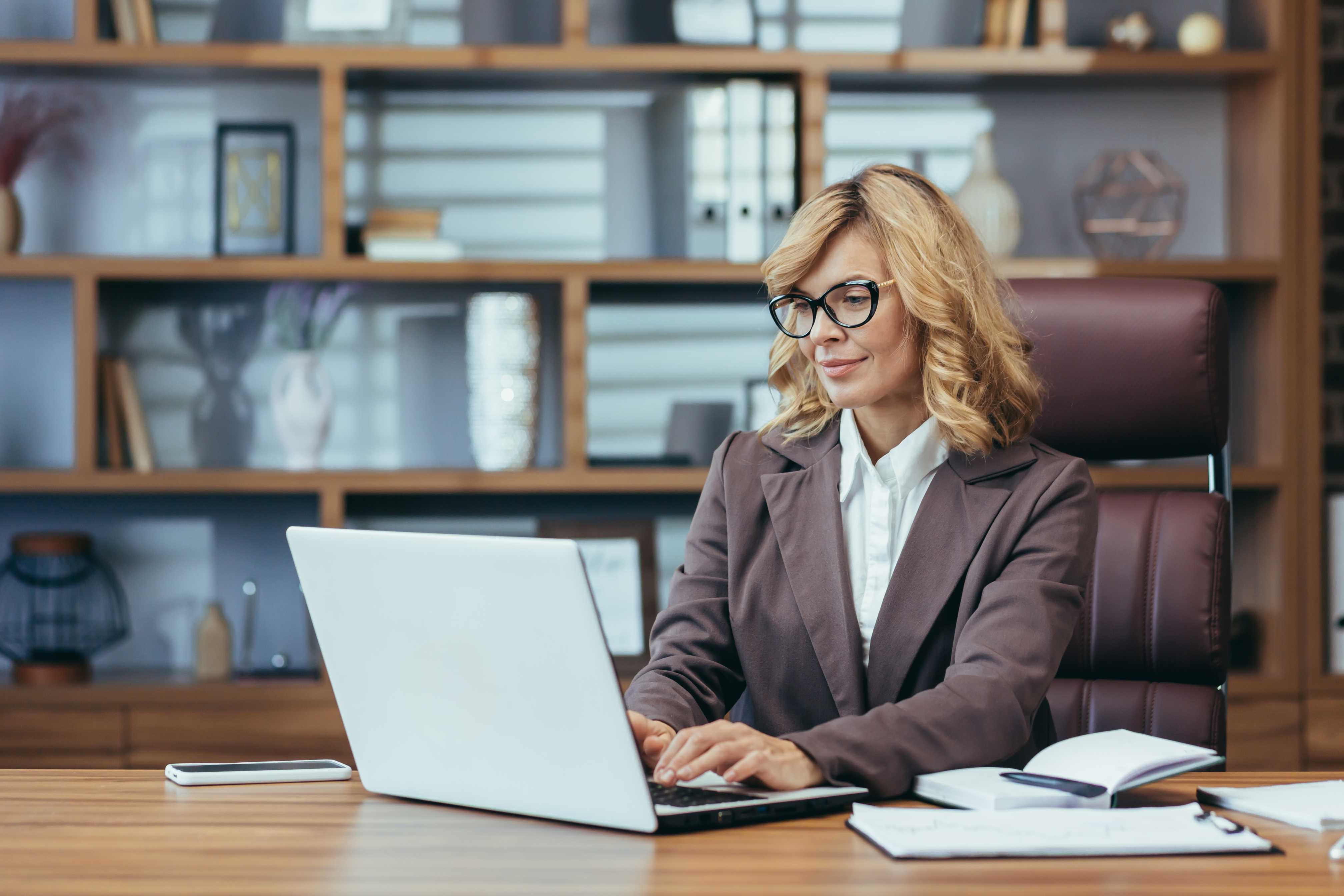 elegant-blonde-senior-businesswoman-focuses-her-laptop-modern-home-office-epitomizing (1)